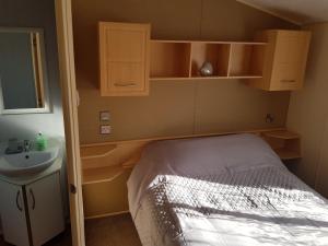 a small bedroom with a bed and a sink at Caravan on Golden Gate Holiday Park in Kinmel Bay