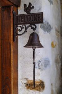 a bell hanging on a wall with a welcome sign at Παραδοσιακό Πηλιορείτικο αρχοντικό στη Βυζίτσα- Traditional villa in Vizitsa, Pelion in Vyzitsa