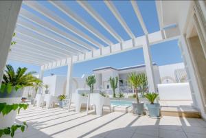 un patio con sillas blancas y una piscina en Dar Benti en Monastir