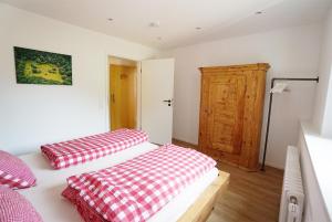 a bedroom with two beds with red and white sheets at Höllkopf - Stubenhof, Black Forest in Simonswald