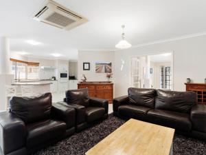 a living room with two leather couches and a table at Aqua La Vista Mandurah in Mandurah