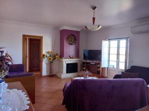 T2,Casa Sol e Mar 50464/AL في فيلا نوفا دو ميلفونتيس: غرفة معيشة مع أثاث أرجواني ومدفأة