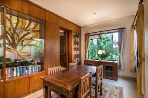 ein Esszimmer mit einem Holztisch und einem Fenster in der Unterkunft The Radian Villa Ubud in Ubud