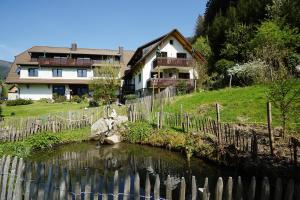 une maison avec une clôture à côté d'une rivière dans l'établissement Höllkopf - Stubenhof, Black Forest, à Simonswald