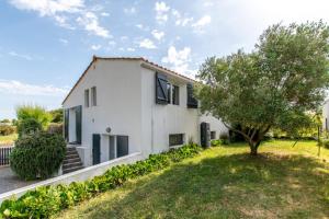 a white house with a tree in front of it at Maison pour 8 personnes au cœur de la Sauzaie et à 600 m de la plage in Brétignolles-sur-Mer