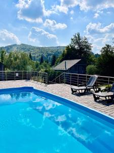 a blue swimming pool with two chairs and a house at Комфортний котедж в Мигово in Migovo