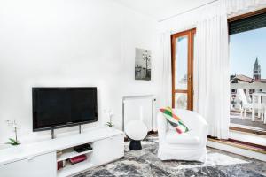 a white living room with a tv and a white chair at Ve-nice Suite Rialto View RT-12 in Venice