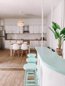 una cocina con armarios blancos y un mostrador y taburetes azules en GreenTree House, en Corralejo