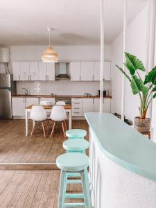 a kitchen with white cabinets and a blue counter and stools at GreenTree House in Corralejo