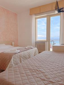 a hotel room with two beds and a large window at Hotel Ambassador in Laigueglia