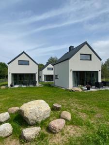 two white houses on a green field with rocks at Chachatki Kopalino in Kopalino