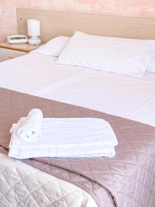 a bed with white sheets and towels on it at Hotel Ambassador in Laigueglia