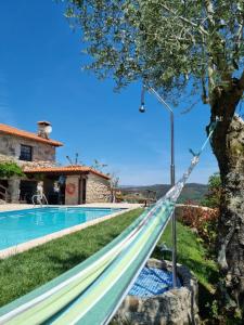 una hamaca junto a la piscina frente a una villa en Casa da Montanha en Rebordões