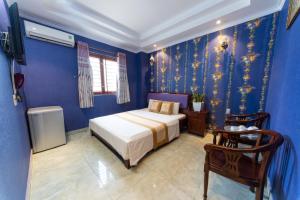 een slaapkamer met blauwe muren en een bed en een stoel bij Ly Ly Hotel in Ho Chi Minh-stad