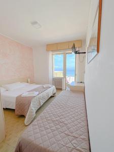 a hotel room with two beds and a window at Hotel Ambassador in Laigueglia