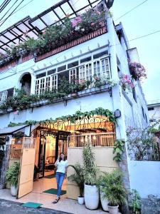 une femme debout devant un bâtiment avec des plantes dans l'établissement Balai Tinay Guesthouse, à Legazpi