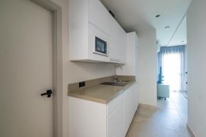 a kitchen with white cabinets and a sink at ON City Apartments in Matalascañas