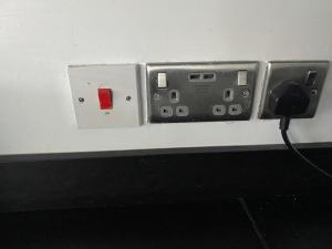 un cable negro conectado a una toma de corriente eléctrica en una pared en Modern 2 bedroom flat with Sky TV & free parking, en Dagenham