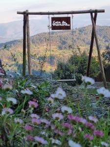 un columpio en un jardín con flores en primer plano en Casa da Montanha en Rebordões