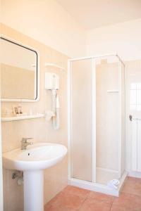 a white bathroom with a shower and a sink at Hotel Ambassador in Laigueglia