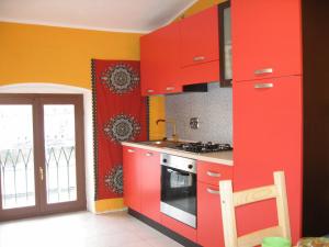 una cucina con armadi rossi e piano cottura di B&B Piazza Vittorio a Torino