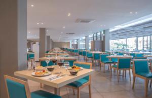 Hotel Roquetas El Palmeral by Pierre & Vacances في روكويتاس دي مار: غرفة طعام مع طاولات وكراسي مع كؤوس للنبيذ