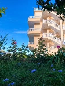 Un grand bâtiment avec des fleurs devant lui dans l'établissement Lumra Rooms, à Lukovë