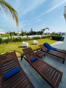 un patio con 2 sillas y 2 tumbonas en By the Beach Villa Natalya en Protaras