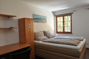 Bett in einem Zimmer mit einem Schreibtisch und einem Fenster in der Unterkunft Apartments-Weberlandl in Wagrain