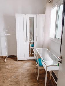 Habitación blanca con mesa de cristal y silla en GreenTree House, en Corralejo
