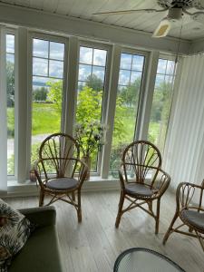 a living room with three chairs and a couch and windows at Villa Båthamnsgatan in Söråker