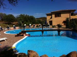 a large swimming pool with chairs and a house at Relais Fenicottero Rosa in Porto San Paolo