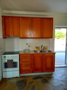 a kitchen with wooden cabinets and a sink and a stove at Athena s House in Platia Ammos
