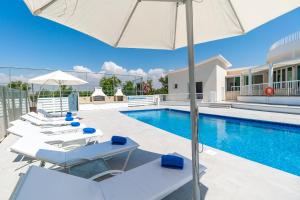 a swimming pool with white lounge chairs and an umbrella at Villa Amelia by Ezoria Villas in Perivolia