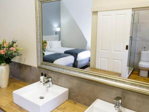a bathroom with a mirror and a sink and a bed at Queens Hotel by BON Hotels in Oudtshoorn