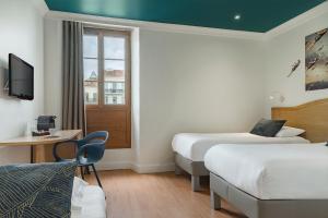 a hotel room with two beds and a window at Grand Hôtel de la Gare Toulon - Boutique Hôtel in Toulon