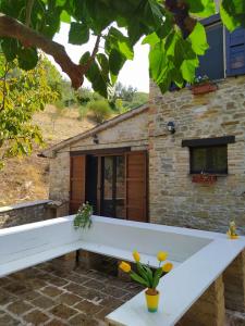 un banco blanco frente a un edificio de piedra en Podere le Serre, en Cingoli