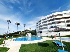 una piscina frente a un edificio con palmeras en Luna Beach Seafront, en Cabopino