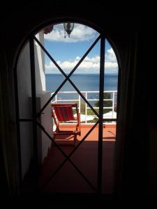 a window with a chair looking out at the ocean at Hostal Piedra Andina in Copacabana