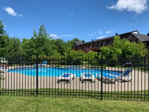 a swimming pool behind a fence with two chairs at L'Authentique in Orford