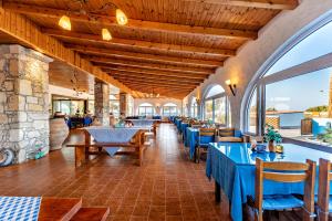 a restaurant with blue tables and chairs and windows at Hotel Tsagarakis Beach in Amoudara Herakliou