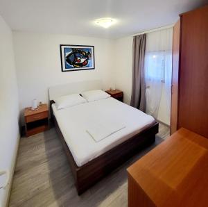 a bedroom with a white bed and two night stands at Apartments Buktenica in Bol