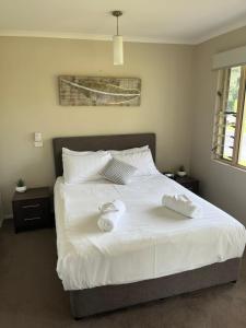 a bedroom with a bed with white sheets and pillows at Reef Terraces on St Crispins in Port Douglas