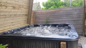 B&B Aquavert & Wellness في تورناي: حوض استحمام ساخن في الفناء الخلفي مع سياج خشبي