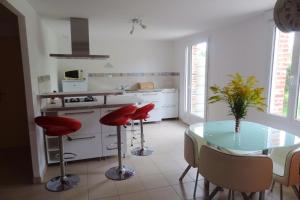 a kitchen with a glass table and red stools at Maison confortable en campagne à Bérengeville-la-campagne + jardin in Bérengeville-la-Campagne +4 photos