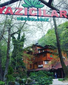 ein Schild für ein Hotel in einem Wald mit einem Gebäude in der Unterkunft Yazicilar Hotel in Masukiye