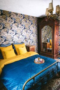 een slaapkamer met een bed met een blauwe deken en een spiegel bij v i o l e t t e La souris des champs in Étival-Clairefontaine