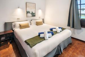 una camera da letto con un grande letto bianco con asciugamani di Conylanza Castillo de Papagayo - Exclusivamente Nudista FKK a Charco del Palo