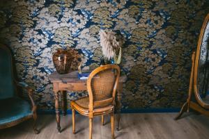 a chair sitting at a table in a room with wallpaper at v i o l e t t e La souris des champs in Étival-Clairefontaine