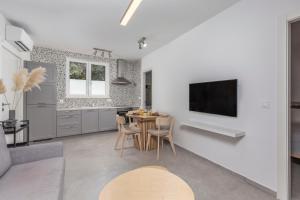 a kitchen and living room with a table and a tv at Apartments Grey, Green i White in Malinska